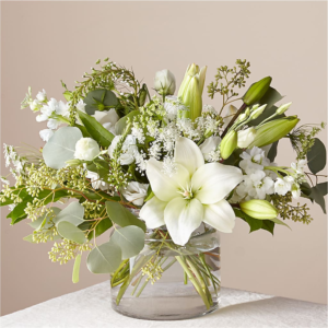 Alluring Elegance Bouquet featuring white lilies and fresh greenery in a glass vase.
