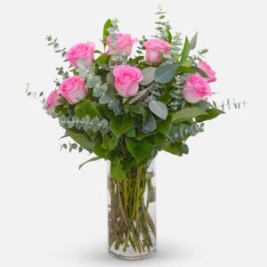 1-dozen pink roses arranged with eucalyptus and lush greenery in a clear glass vase