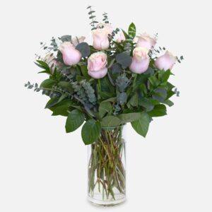 1-dozen soft pink roses arranged with eucalyptus and lush greenery in a clear glass vase