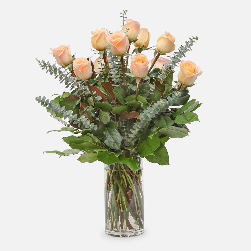 1-dozen peach roses arranged with eucalyptus and lush greenery in a clear glass vase