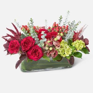 Red and green floral centerpiece in a glass vase