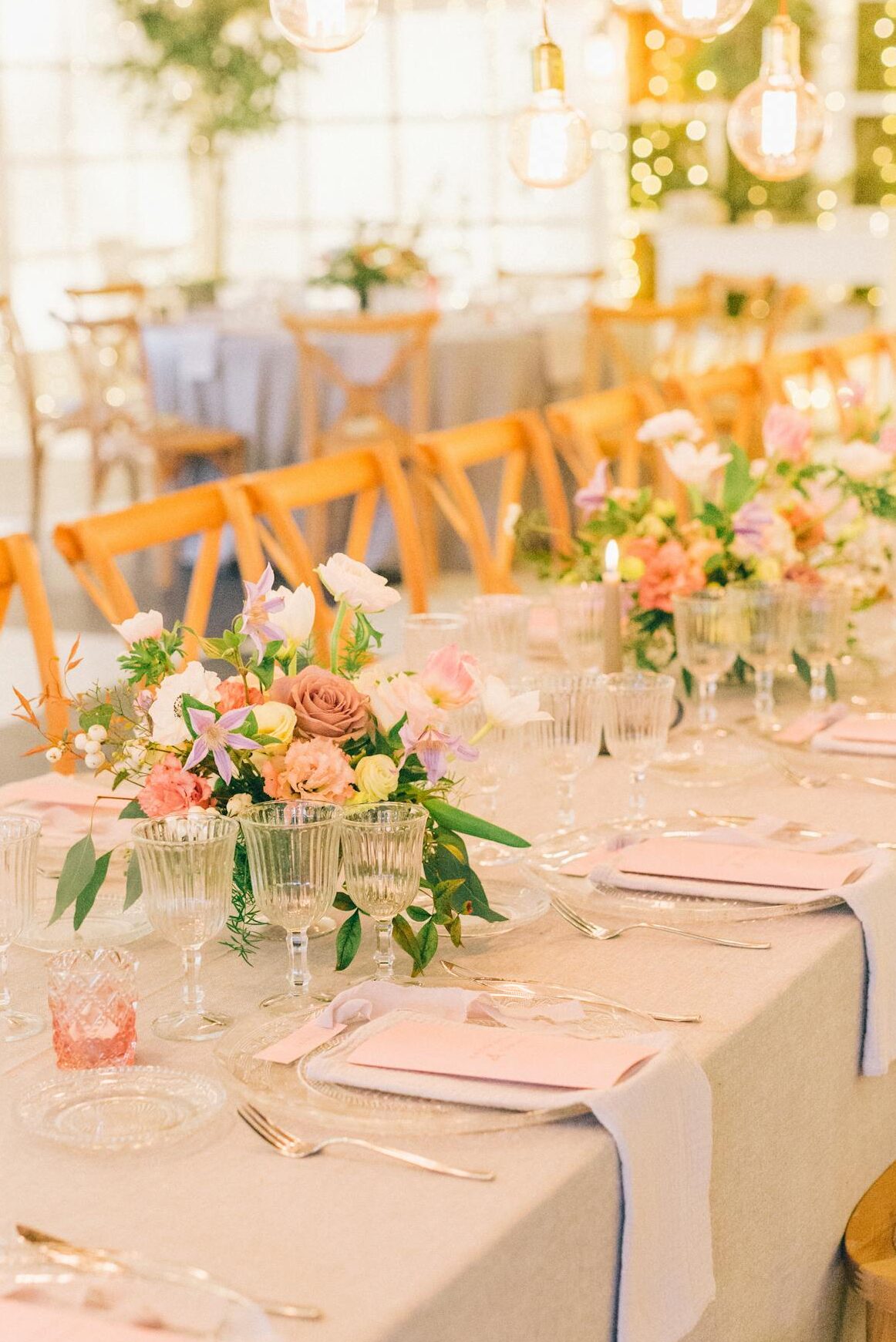 Stylish wedding table setting with floral arrangements and warm lighting.